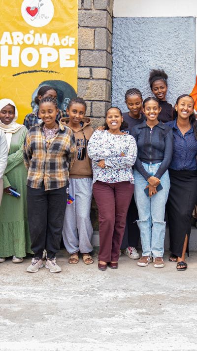 Young students gather on the Life Center Ethiopia campus in front of the Aroma of Hope banner during summer programming.