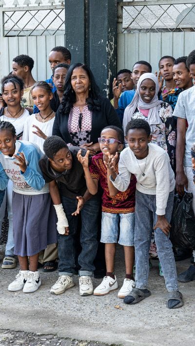 Founder and director Mulu Woldetinsae stands with sponsored children and youth outside the Life Center Ethiopia campus.