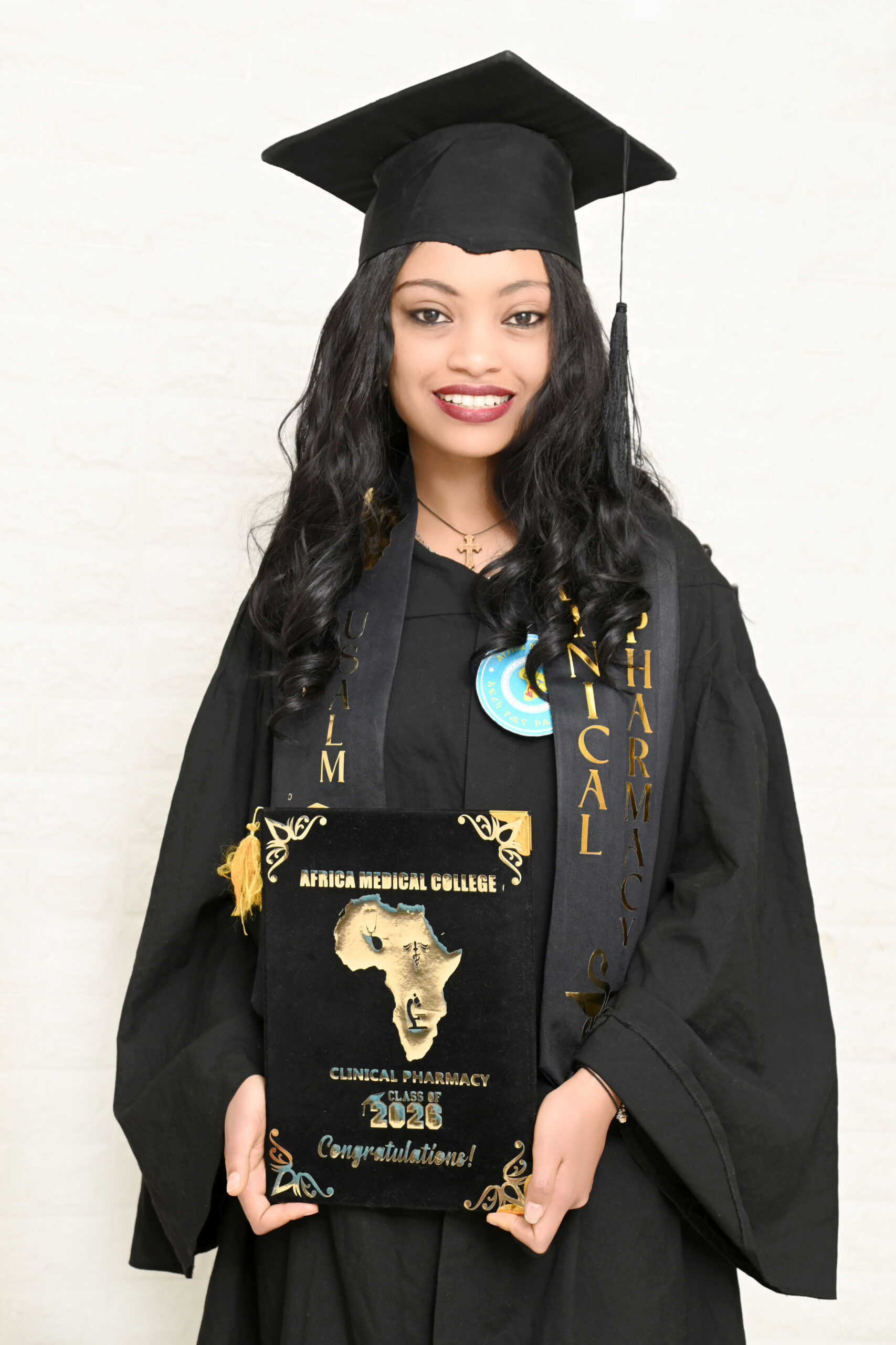 LCE sponsored student Eyerusalem smiling proudly while holding her Clinical Pharmacy degree from Africa Medical College during her graduation ceremony.