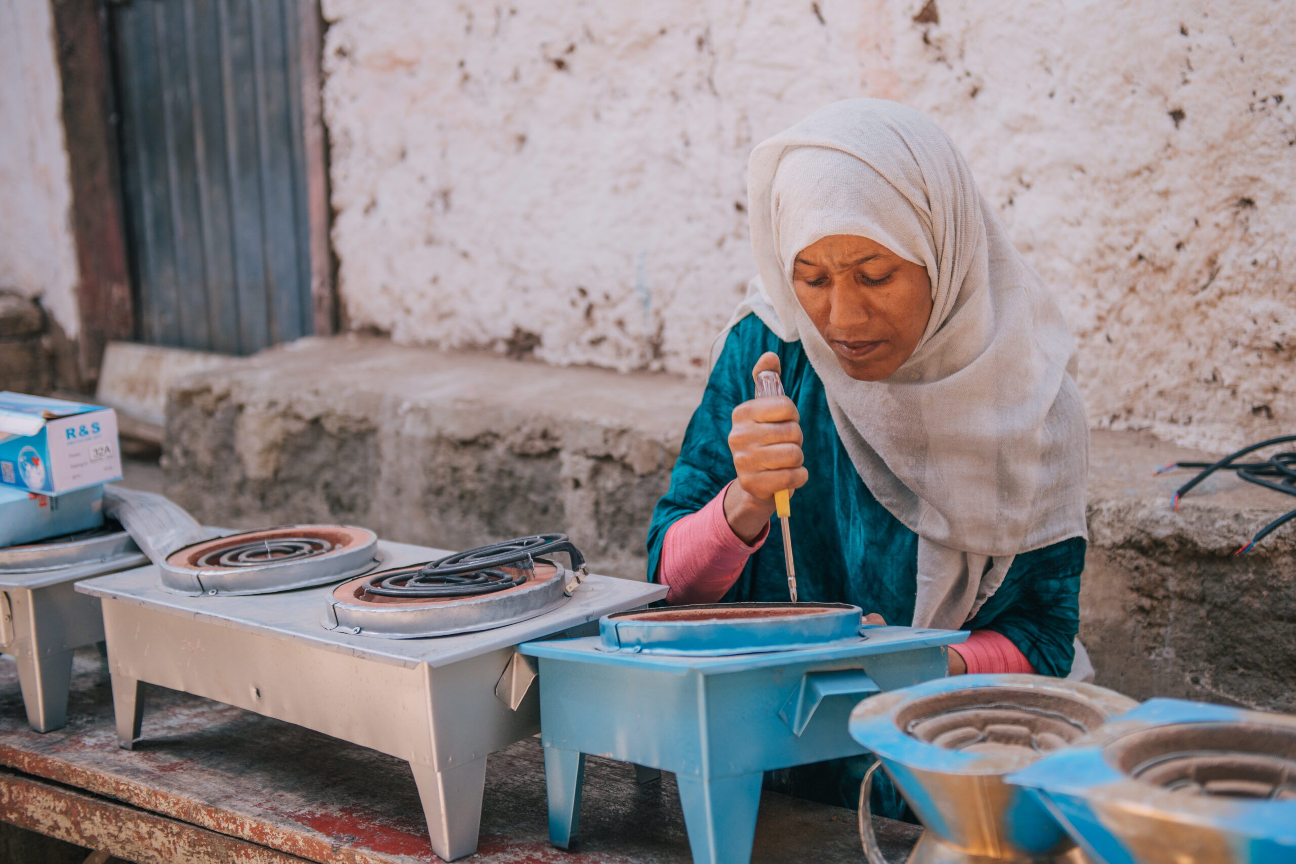 An Ethiopian entrepreneur named Nurit focusing intently while assembling an electric cooking stove during an LCE trade training workshop.