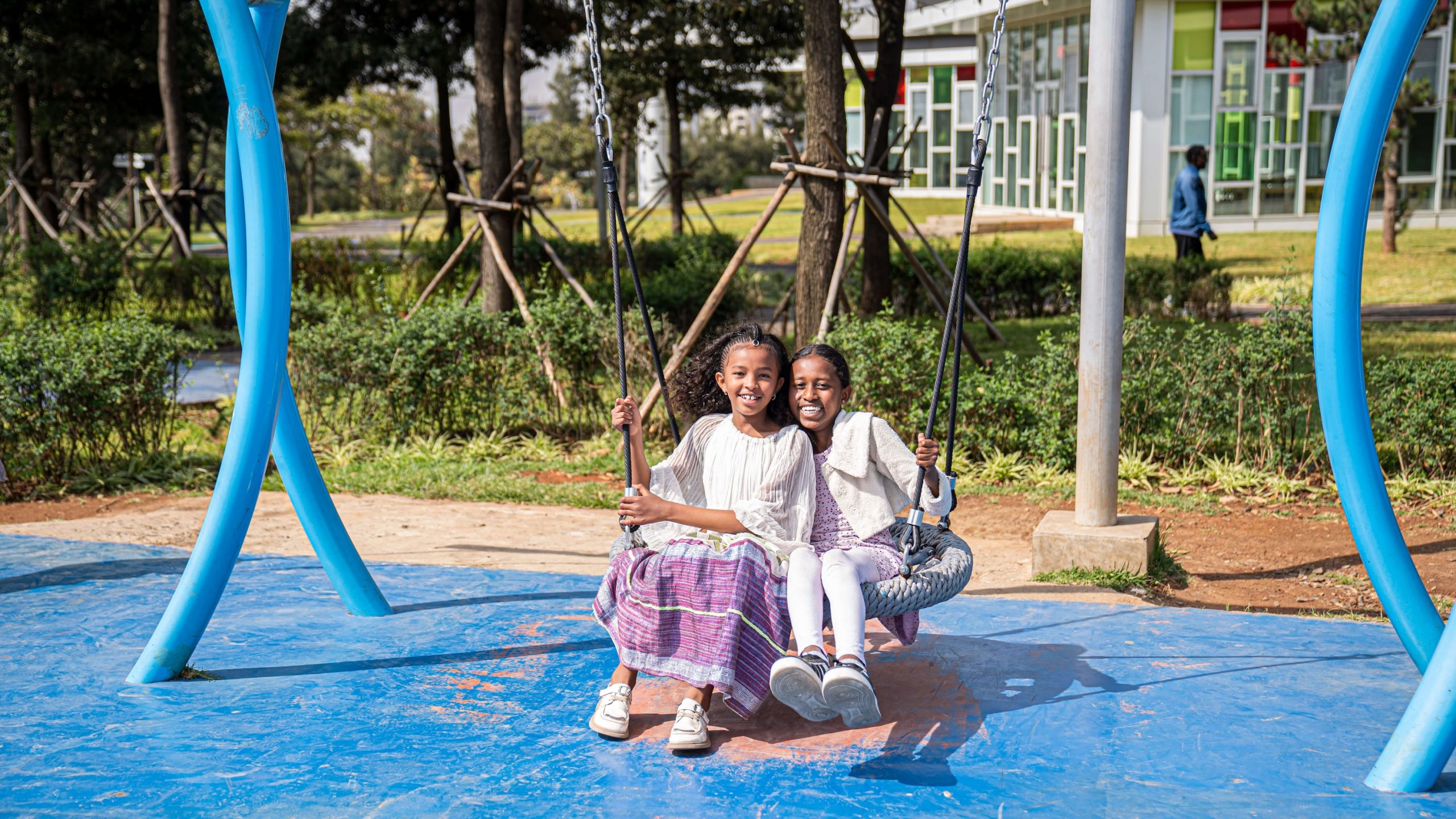 Two children at Life Center Ethiopia smiling together on a playground swing